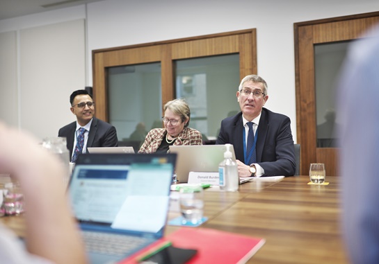 Image of three people in a meeting around a table