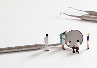 miniature people looking in dental mirror
